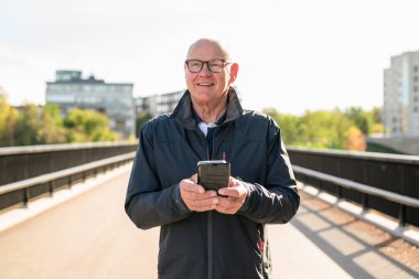 Happy senior man using mobile phone in the city. Technology concept.