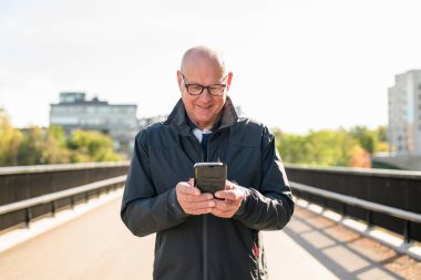 Happy senior man using mobile phone in the city. Technology concept.