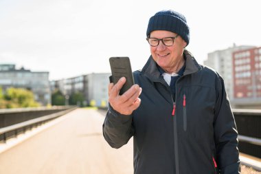 Happy senior man using mobile phone in the city. Technology concept.