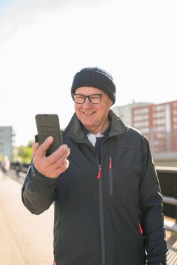 Happy senior man using mobile phone in the city. Technology concept.