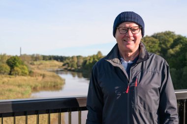 Portrait of a smiling Scandinavian senior man in sportswear on the bridge