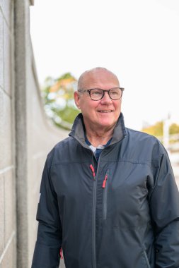 Portrait of a smiling senior man with eyeglasses in the city thinking