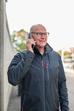 Portrait of senior man talking on cell phone in the street.