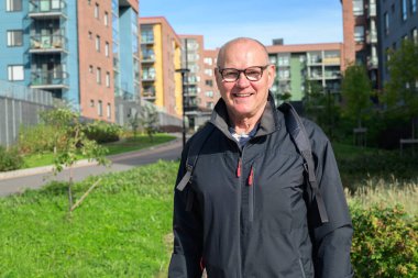 Smiling senior man standing in a residential area, looking at the camera