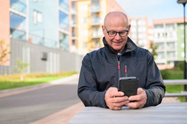 Portrait of a senior man using his mobile phone in urban environment