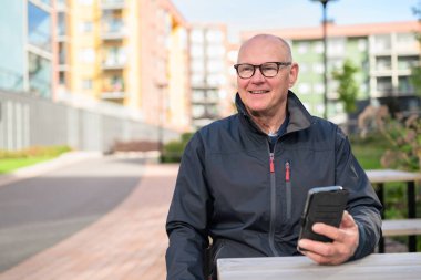 Portrait of a senior man using his mobile phone in urban environment