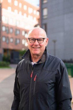 Smiling senior man standing in a residential area, looking at the camera