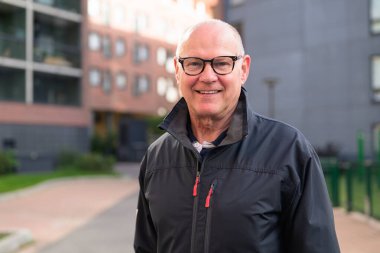 Smiling senior man standing in a residential area, looking at the camera