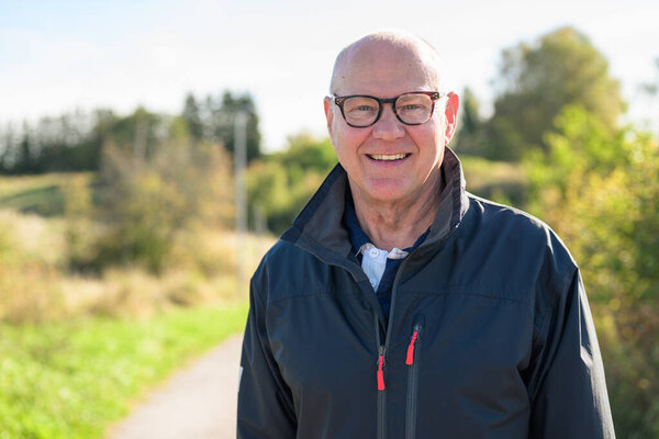 Portrait of a smiling Nordic senior man in sportswear standing outdoors looking at camera