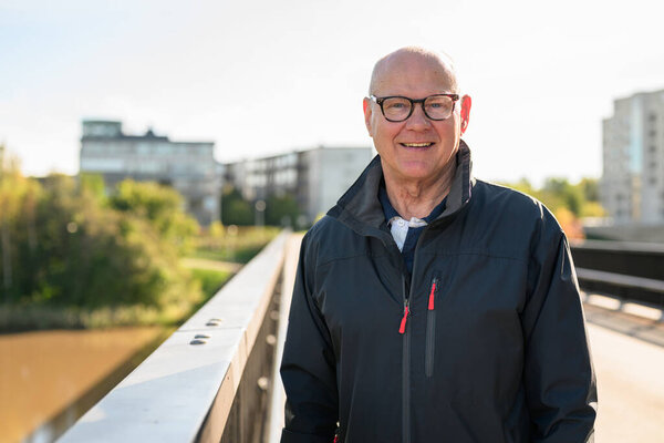 Portrait of a smiling Scandinavian senior man standing on a bridge in the city