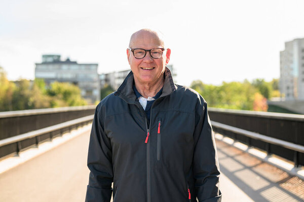 Portrait of a smiling Scandinavian senior man standing on a bridge in the city