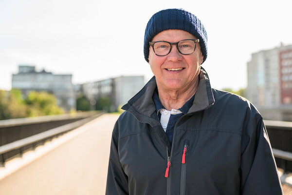 Portrait of a smiling senior man in sportswear on the bridge