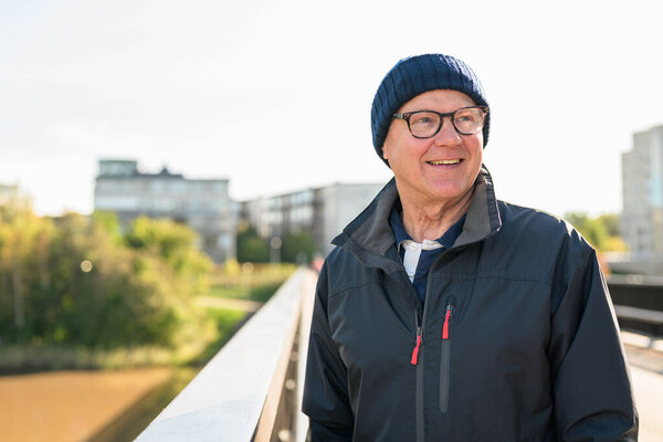 Portrait of a smiling senior man in sportswear on the bridge