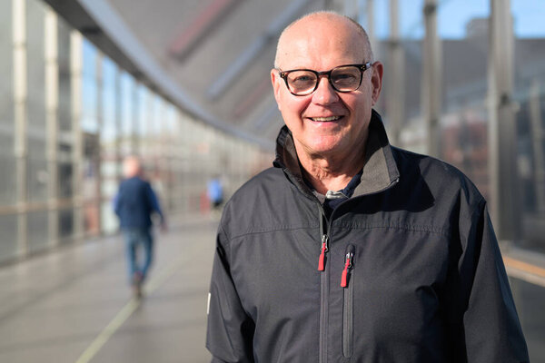 Portrait of a bald senior man wearing glasses and a jacket in train station bridge