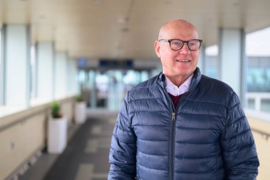 Portrait of a smiling senior man in the corridor of an airport