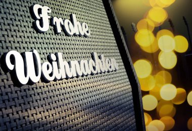 Alman Mutlu Noeller rozetine sahip bir gitar amfisini kapat ve bulanık Noel ışıkları, arka planda bulanık gitarlar, 3 boyutlu görüntüler...