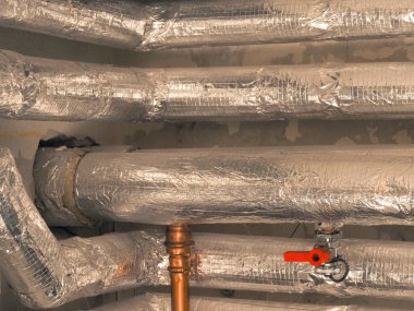 Isıtma boruları bir kazan dairesinde yalıtılmış kaya yünü ile yalıtılmış. Enerji tasarrufu ve enerji maliyeti azaltma kavramı, iklim değişikliği