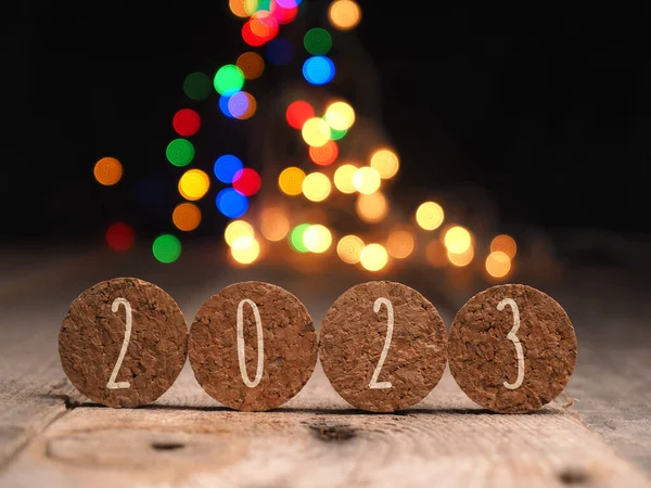 크리스마스등 배경에 새겨진 2023 문구가 새겨진 모양의 코르크 — 스톡 사진