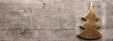 Kırsal ahşap bir tahtanın üzerinde altın Noel ağacı şekli ve metin için yeri var.