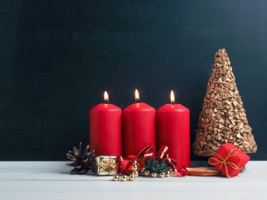 Üçüncü Advent mumları, Noel süslemeleri ile birlikte karatahtada, mevsimlik veya tatil arka planında yanıyor.