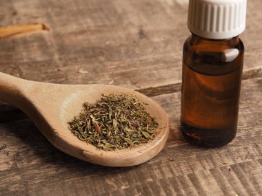 Tahta bir kaşıkta kurutulmuş kekik yağı ve sağlıklı malzemeler.