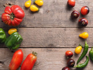 Kırsal ahşap mutfak masasında domates ve biber çeşitleri, yukarıdan görüş, metin veya resim için alan