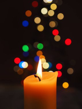 Bulanık Noel ışıkları ve güzel romantik Noel arkaplanı ile yanan bir mum.