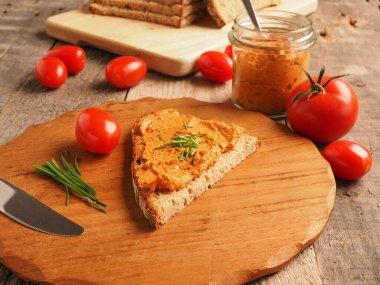 Frenk soğanı ve sağlıklı gıda konseptiyle süslenmiş kırsal heceli ekmeğe yayılmış organik vejetaryen domates.