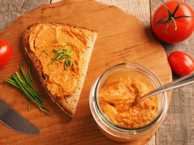 Frenk soğanı ve sağlıklı gıda konseptiyle süslenmiş kırsal heceli ekmeğe yayılmış organik vejetaryen domates.