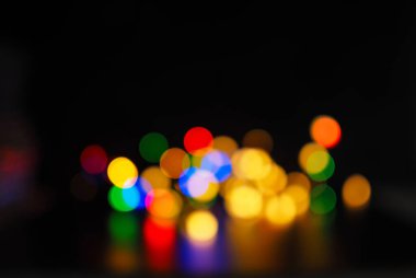 Kaplama ya da arkaplan olarak kullanılan koyu arkaplan üzerindeki bulanık Noel ışıkları, metin ya da resim için boşluk