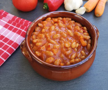 Masada domates soslu fırında pişmiş fasulye kasesi. 