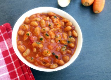 Masada domates soslu fırında pişmiş fasulye kasesi. 