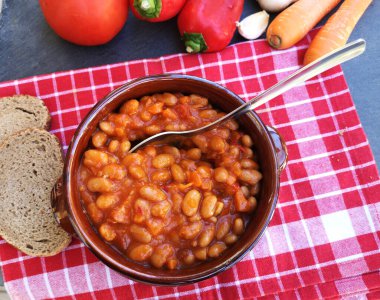 Ceramic bowl of baked beans with tomato sauce on the table  clipart