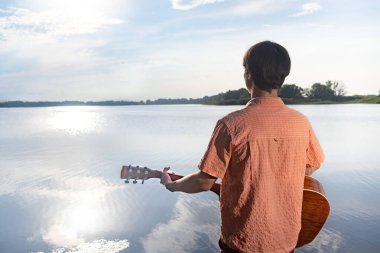 Rıhtımda gitar çalan bir adam. Güzel doğal manzara