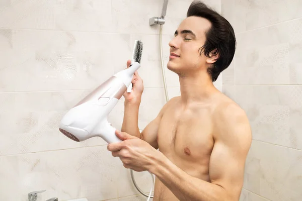 洗完澡后 男人用吹风机吹风他的头发 — 图库照片