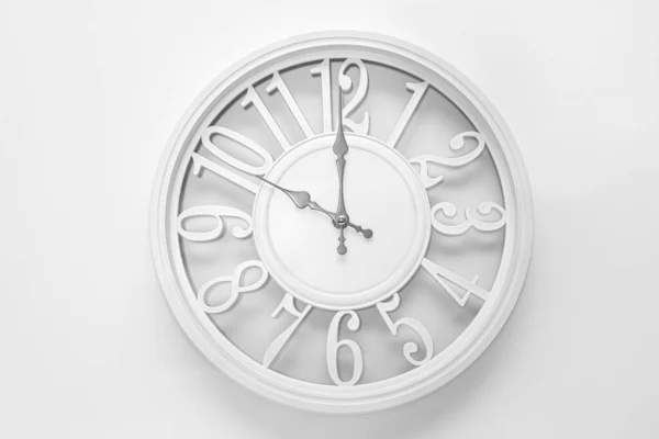 Modern white clock with a circle on a white wall background, ten o'clock on the clock