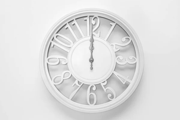 Modern white clock with a circle on a white wall background, twelve o\'clock on the clock