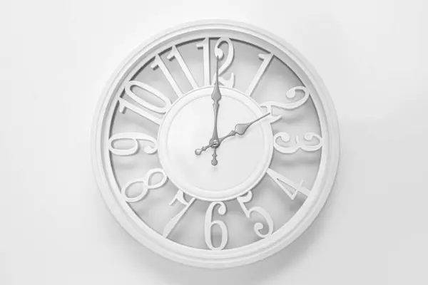 Modern white clock with a circle on a white wall background, two o\'clock on the clock