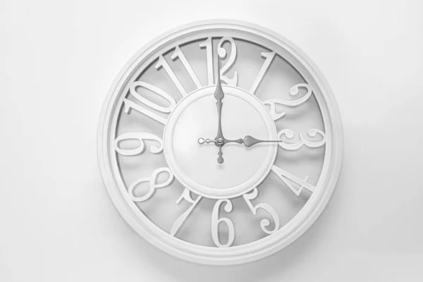 Modern white clock with a circle on a white wall background, three o\'clock on the clock