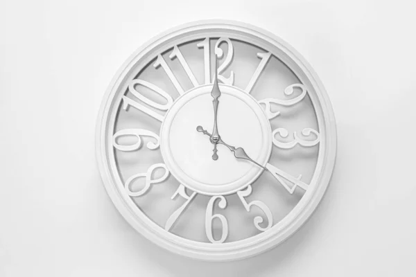 Modern white clock with a circle on a white wall background, four o\'clock on the clock