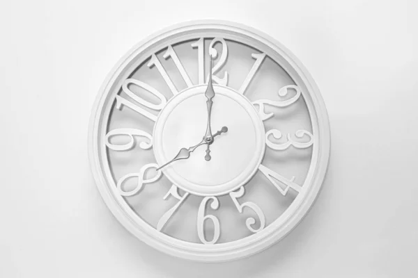 Modern white clock with a circle on a white wall background, eight o'clock on the clock