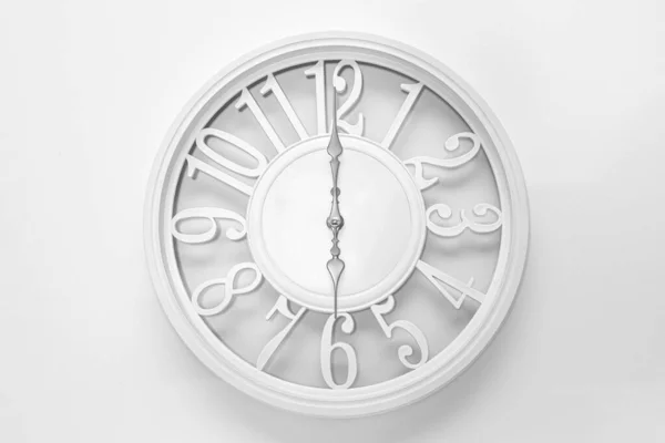 Modern white clock with a circle on a white wall background, six o\'clock on the clock