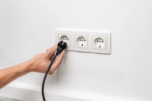 Human Hand Unplugging Black Cable Triple White Electrical Outlet White — Stock Photo, Image