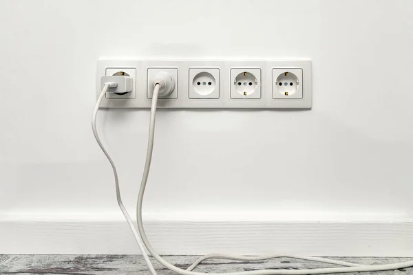 白色的五边形电源插座安装在白墙上 配有插入式电话适配器和白色电源插座 前视图 — 图库照片