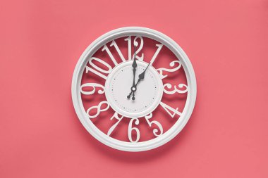 Pembe duvar zemininde bir dairesi olan modern beyaz saat, saat bir yönünde. Barbekü tarzında zarif bir saat, beyaz ve pembe renklerin kombinasyonu