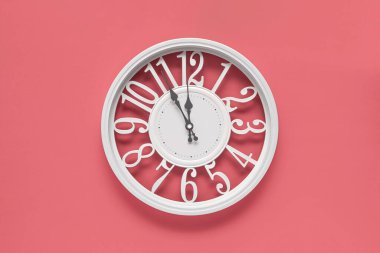 Pembe duvar zemininde bir dairesi olan modern beyaz saat, saat beşten on ikiye kadar. Barbekü tarzında zarif bir saat, beyaz ve pembe renklerin kombinasyonu