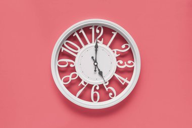 Pembe duvar zemininde dairesi olan modern beyaz saat, saat 5 yönünde. Barbekü tarzında zarif bir saat, beyaz ve pembe renklerin kombinasyonu