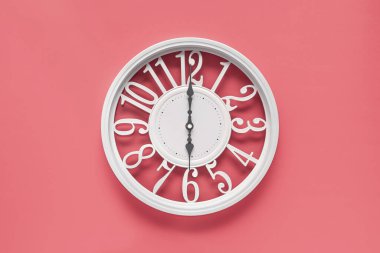 Pembe duvar zemininde dairesi olan modern beyaz saat, saat altı yönünde. Barbekü tarzında zarif bir saat, beyaz ve pembe renklerin kombinasyonu