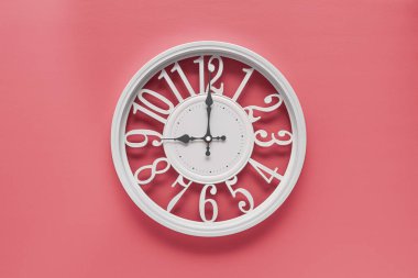 Pembe duvar zemininde dairesi olan modern beyaz saat, saat dokuz yönünde. Barbekü tarzında zarif bir saat, beyaz ve pembe renklerin kombinasyonu