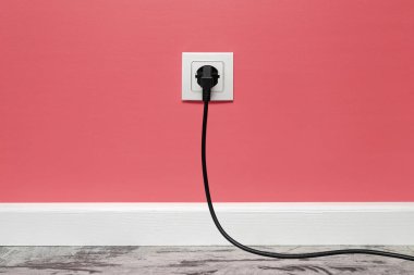 Pembe duvara monte edilmiş beyaz prizle siyah elektrik prizi, ön görüş..